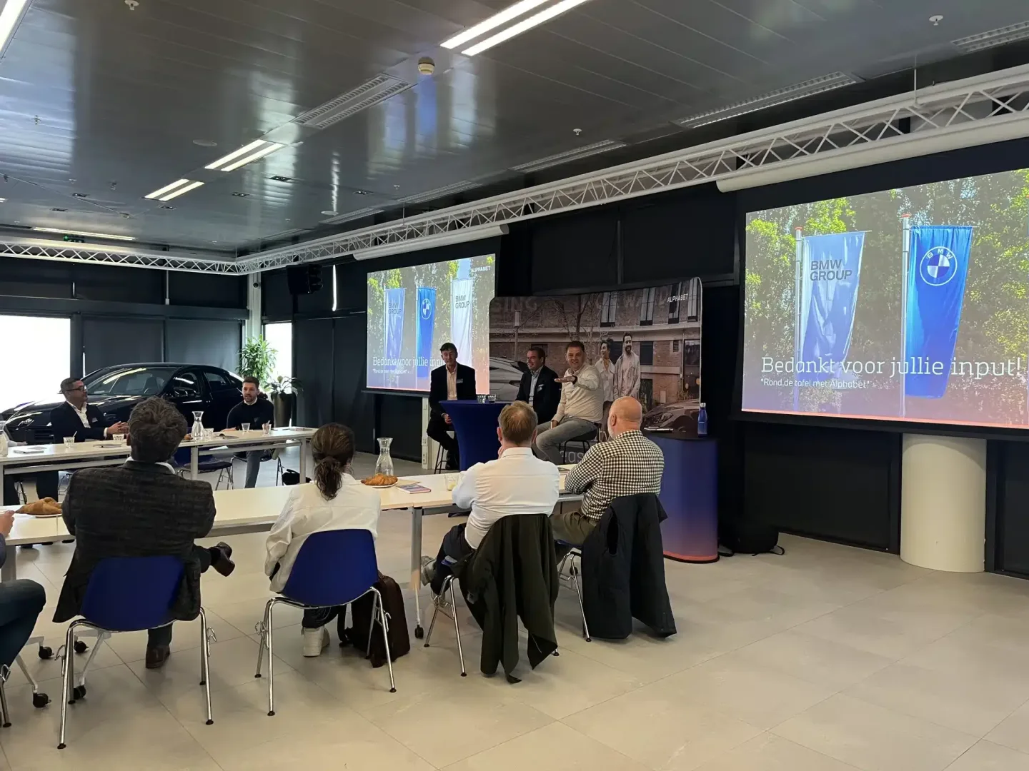 Ronnie Couwenberg leidt een paneldiscussie tijdens een klantevent van Alphabet en BMW in een professionele setting.