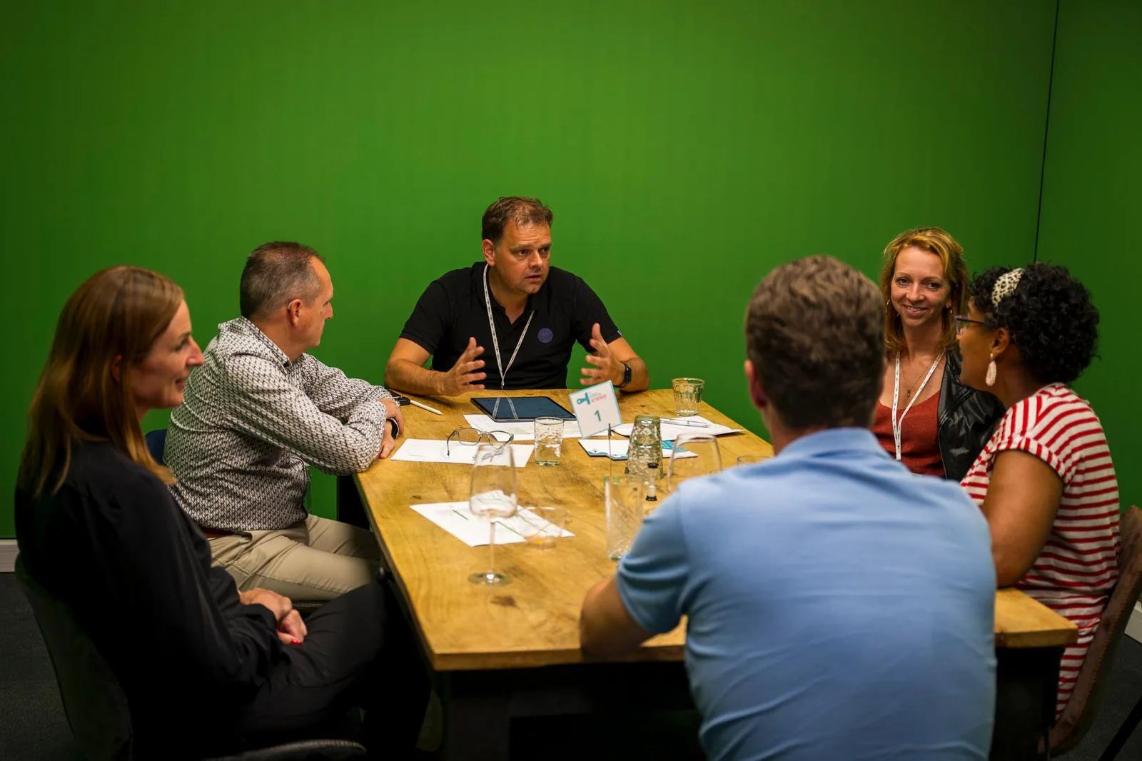 Ronnie Couwenberg leidt een gesprek aan tafel met vijf mensen.