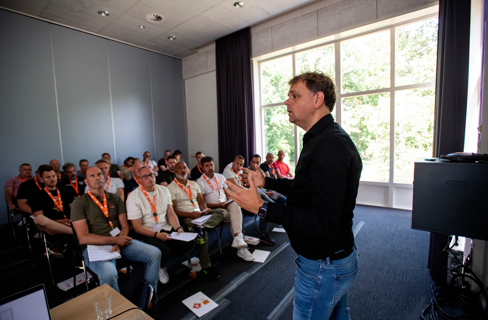 Ronnie Couwenberg staat voor een groep coaches en legt met zijn handen iets uit.